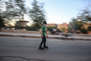 Ung person i munskydd åker rullskridskor på en stadsgata