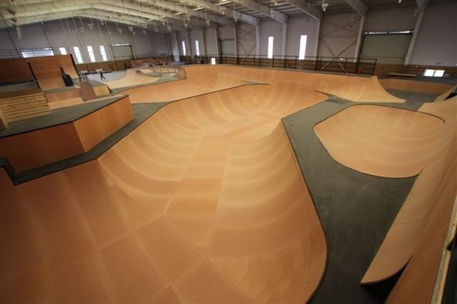 Stor inomhuspark med träklädda bowls och ramper för skateboard