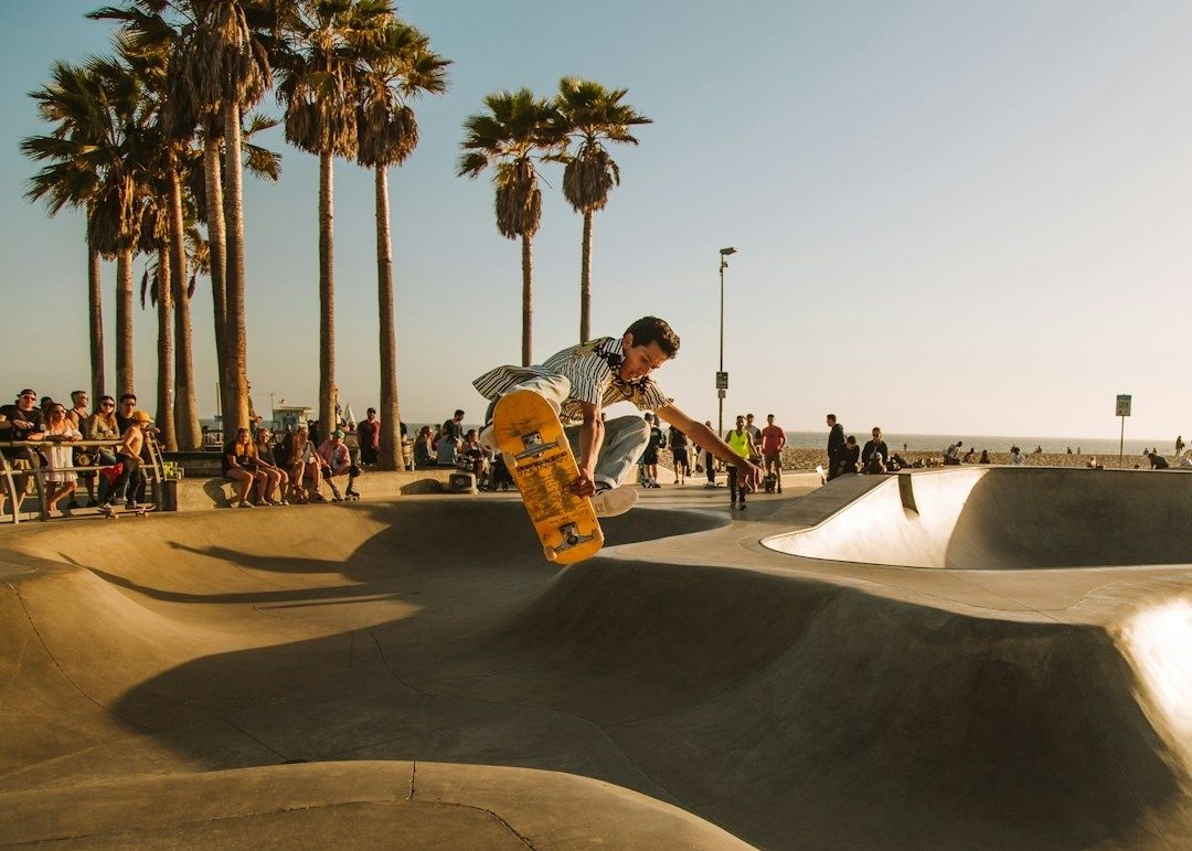 Skateboardåkare gör ett lufttrick i en solbelyst betongpark vid havet